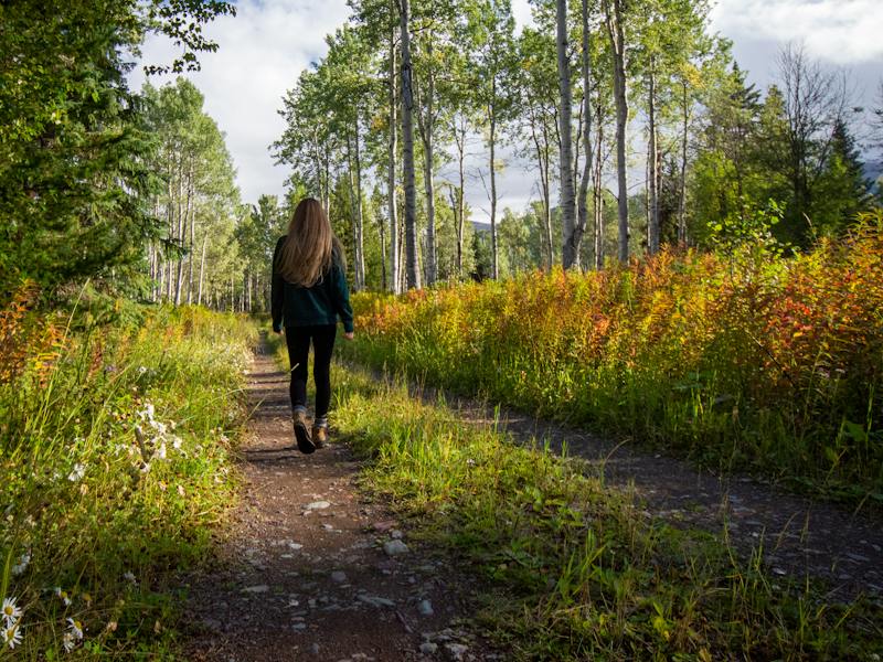 A young person walking along a path through the woods
